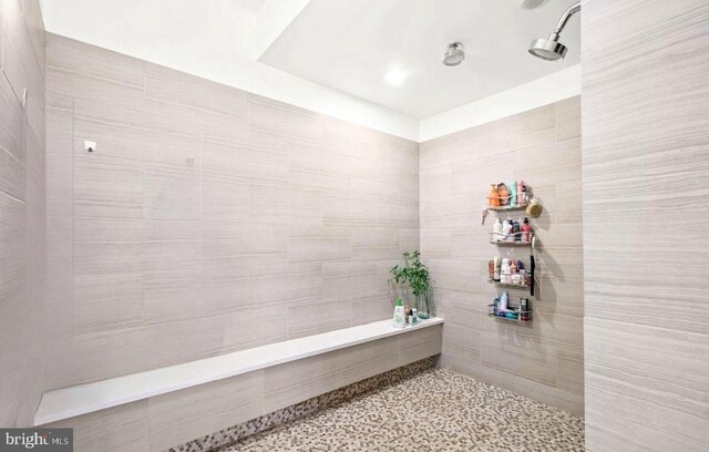 full bath featuring a tile shower and speckled floor