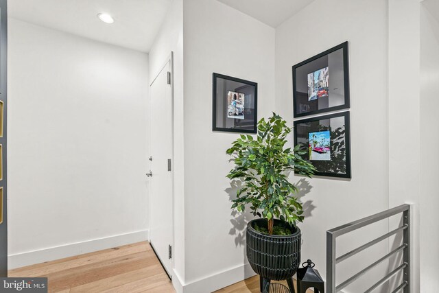 corridor with wood finished floors, baseboards, and recessed lighting