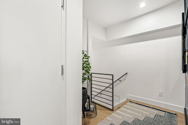 hallway featuring an upstairs landing, wood finished floors, recessed lighting, and baseboards