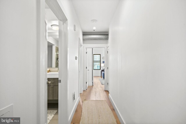 corridor featuring light wood finished floors and baseboards