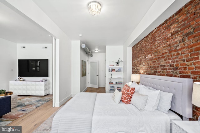 bedroom featuring wood finished floors, brick wall, and baseboards