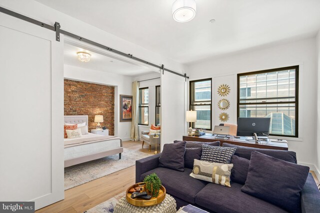 living room featuring a barn door, light wood-type flooring, a desk, and baseboards