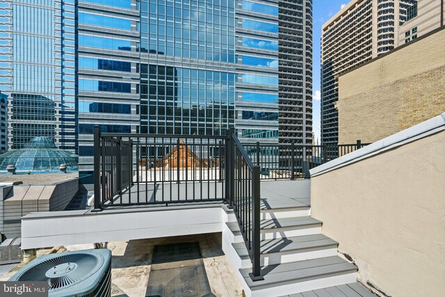 view of patio with a balcony, central air condition unit, and a view of city