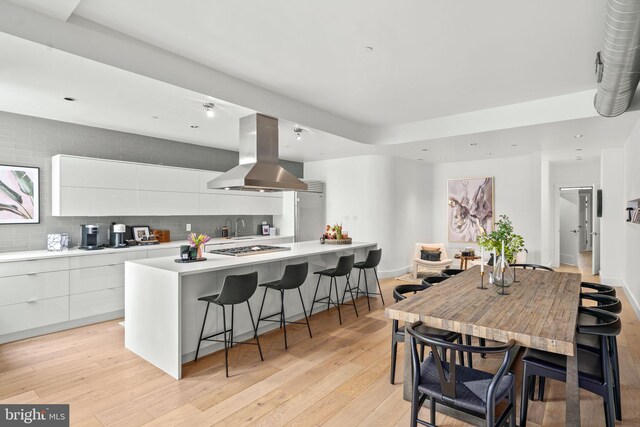 kitchen with island range hood, modern cabinets, white cabinetry, a kitchen bar, and a center island