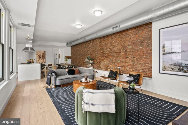 living room with wood-type flooring and brick wall