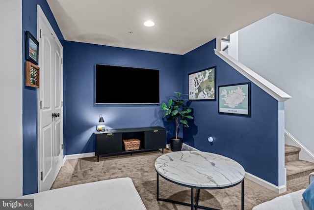 carpeted living area with stairway and baseboards