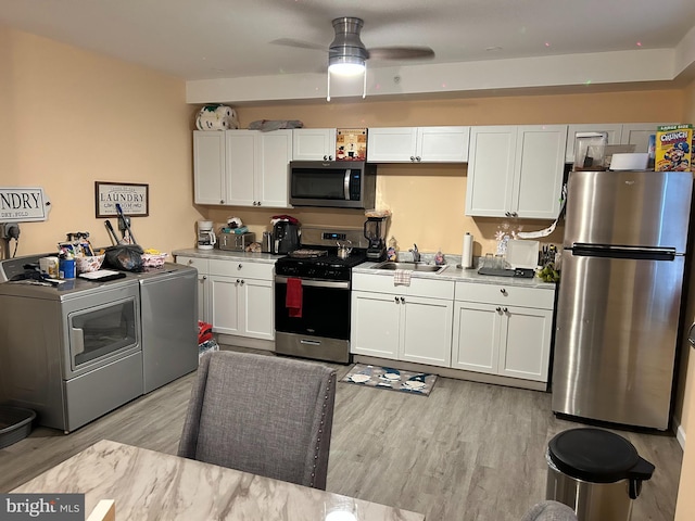 402 Market St, Marcus Hook, PA 19061 - kitchen with washing machine and clothes dryer, appliances with stainless steel finishes, a sink, and white cabinets