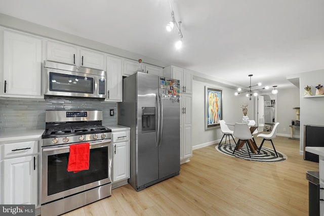 kitchen with appliances with stainless steel finishes, light countertops, white cabinetry, and backsplash