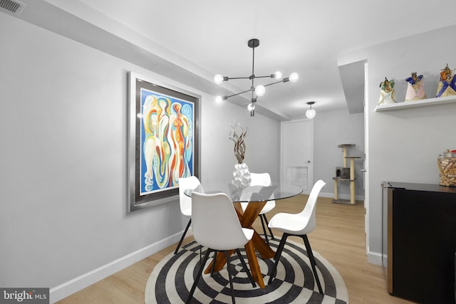 dining room with a chandelier, light wood-style floors, and baseboards