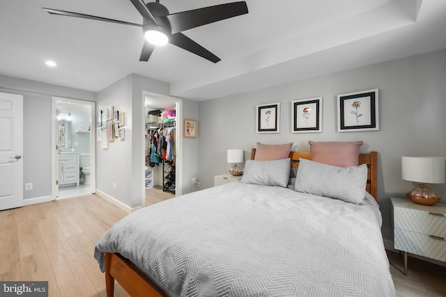 bedroom featuring a walk in closet, light wood-style floors, recessed lighting, baseboards, and a closet