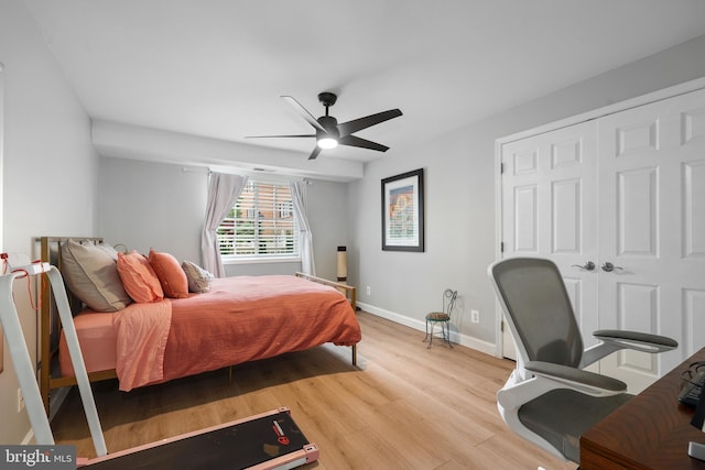 bedroom with wood finished floors, baseboards, ceiling fan, and a closet