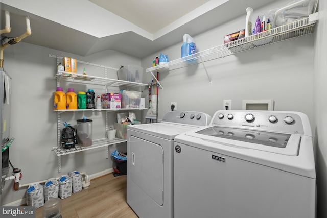 clothes washing area featuring independent washer and dryer, light wood finished floors, and baseboards