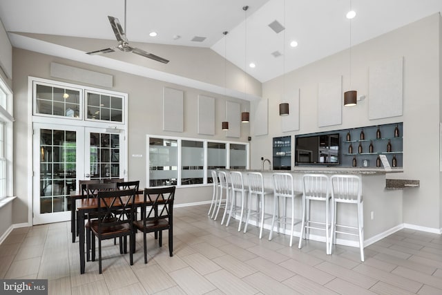 kitchen featuring a ceiling fan, a breakfast bar area, high vaulted ceiling, a peninsula, and white cabinets