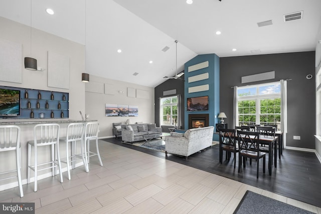 living area featuring a warm lit fireplace, lofted ceiling, a ceiling fan, recessed lighting, and baseboards
