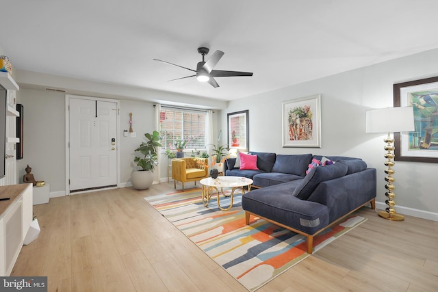 living room with ceiling fan, light wood finished floors, and baseboards