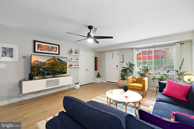 living room with light wood-type flooring, a ceiling fan, and baseboards