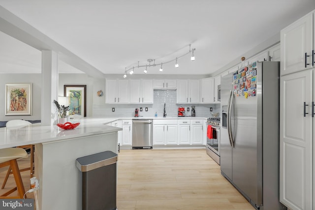 kitchen featuring appliances with stainless steel finishes, a peninsula, and white cabinets