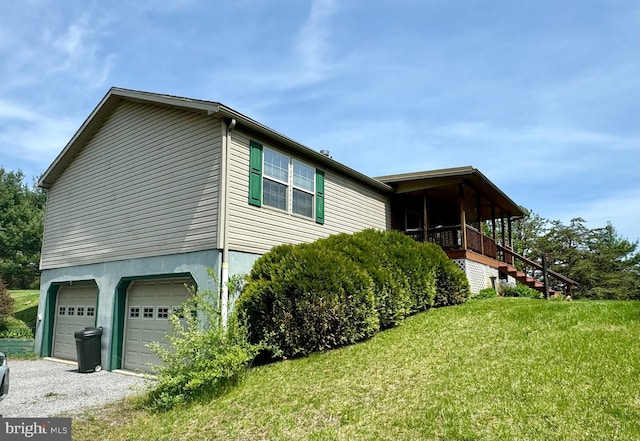 view of property exterior with a lawn, a garage, gravel driveway, and stairway
