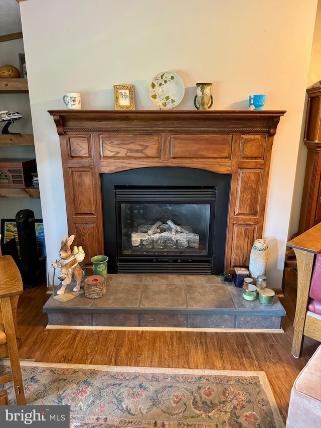 detailed view of wood finished floors and a fireplace with raised hearth