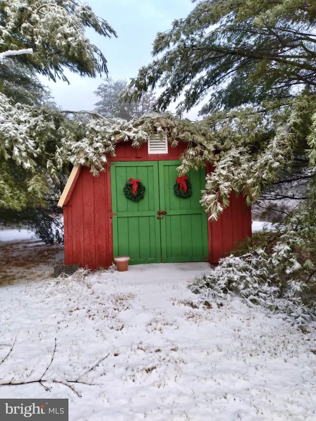 snow covered structure featuring a storage unit and an outdoor structure