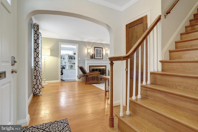 2914 6th St S, Arlington, VA 22204 - foyer with arched walkways, a fireplace, crown molding, light wood-style flooring, and stairs