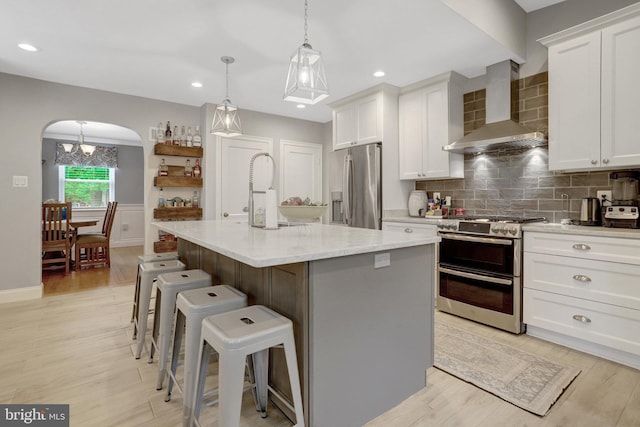2914 6th St S, Arlington, VA 22204 - kitchen featuring stainless steel appliances, wall chimney range hood, arched walkways, white cabinets, and recessed lighting