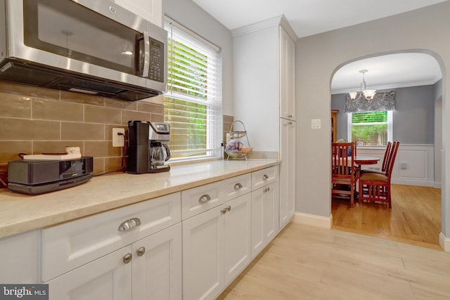 2914 6th St S, Arlington, VA 22204 - kitchen with stainless steel microwave, arched walkways, a chandelier, white cabinets, and decorative backsplash