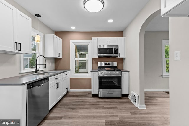 537 Baer Ave, Hanover, PA 17331 - kitchen featuring appliances with stainless steel finishes, a sink, arched walkways, wood finished floors, and white cabinetry
