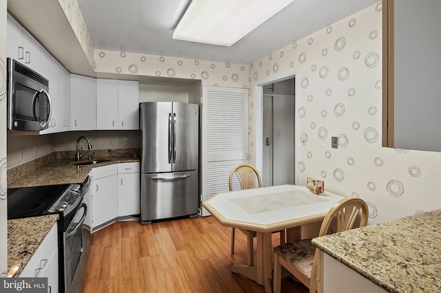 2 High Stepper Ct Unit 201, Baltimore, MD 21208 - kitchen with stainless steel appliances, a sink, light wood-style floors, white cabinets, and light stone countertops