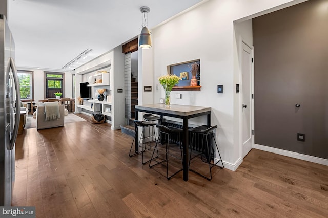dining space featuring wood finished floors, baseboards, and track lighting