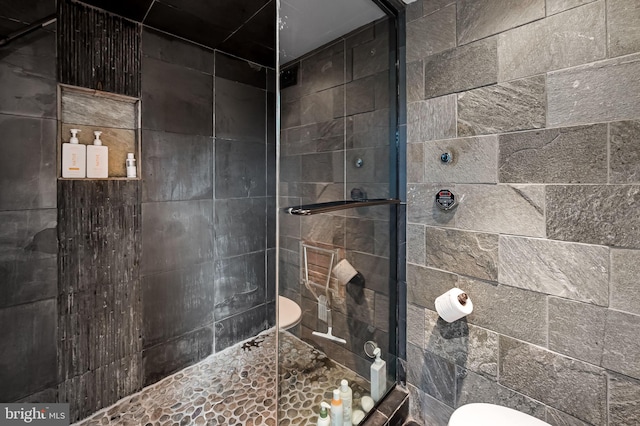 bathroom with tiled shower and toilet