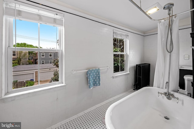 bathroom featuring radiator, a soaking tub, and curtained shower