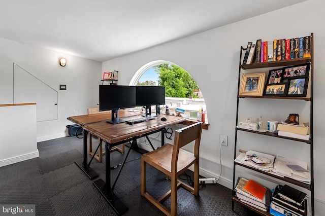 home office with dark carpet and baseboards