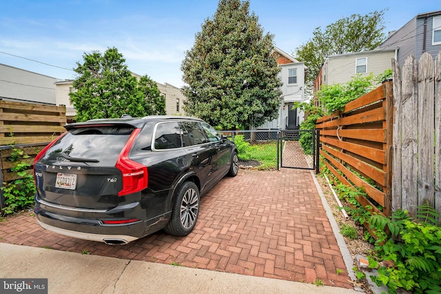 view of vehicle parking with a gate and fence