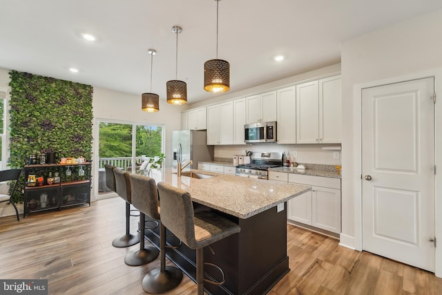 7853 Bluelick Run Rd, Baltimore, MD 21244 - kitchen with stainless steel appliances, a kitchen island with sink, light wood-type flooring, white cabinets, and recessed lighting