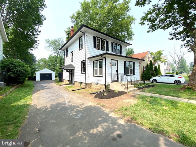 american foursquare style home with a chimney, a garage, asphalt driveway, an outdoor structure, and a front lawn