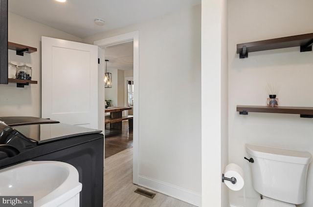 bathroom featuring wood finished floors, toilet, and baseboards