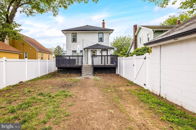 back of house with a fenced backyard, a deck, a gate, and a chimney