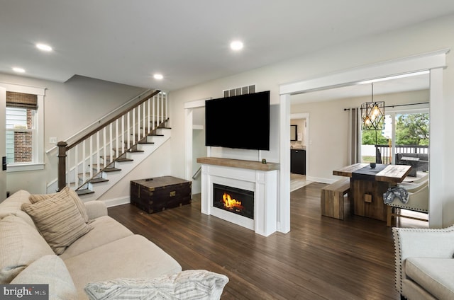 living room featuring wood finished floors, baseboards, stairway, recessed lighting, and a lit fireplace