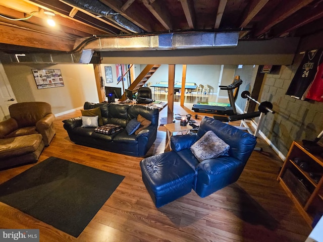 living room with stairway, wood finished floors, and concrete block wall