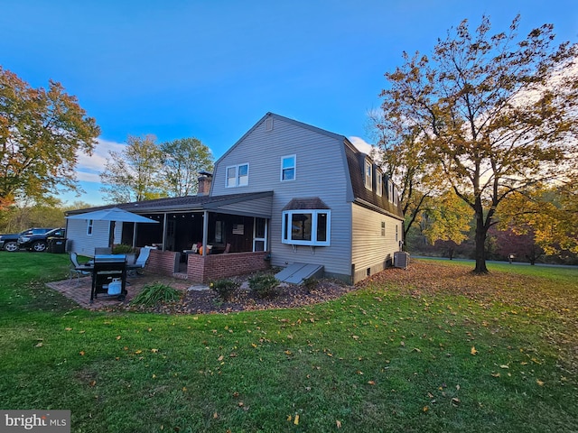 back of property with a sunroom, a yard, central air condition unit, and a chimney