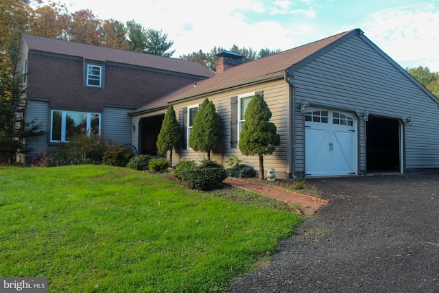 dutch colonial featuring a garage, a chimney, and a front lawn