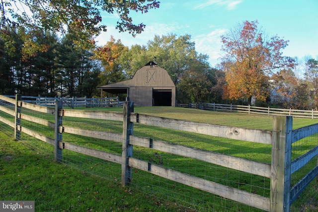 view of yard with a barn, a garage, an outdoor structure, and a view of countryside