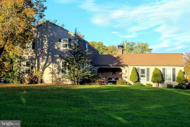 view of front facade with a front yard and a chimney