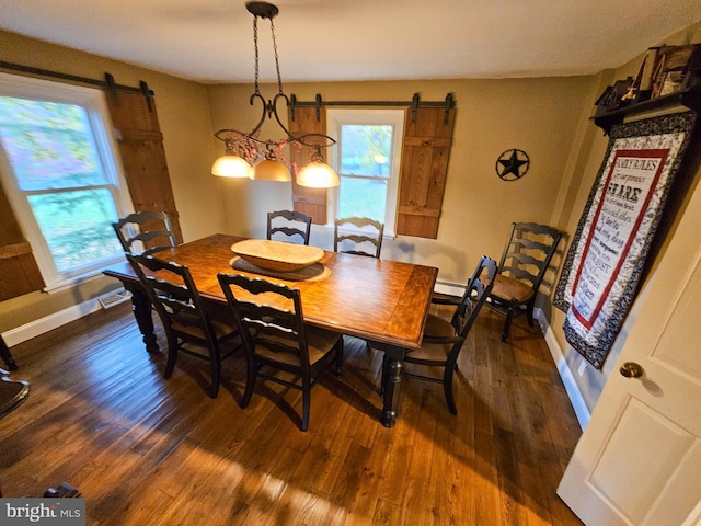 dining area featuring a barn door, dark wood-style floors, and baseboards