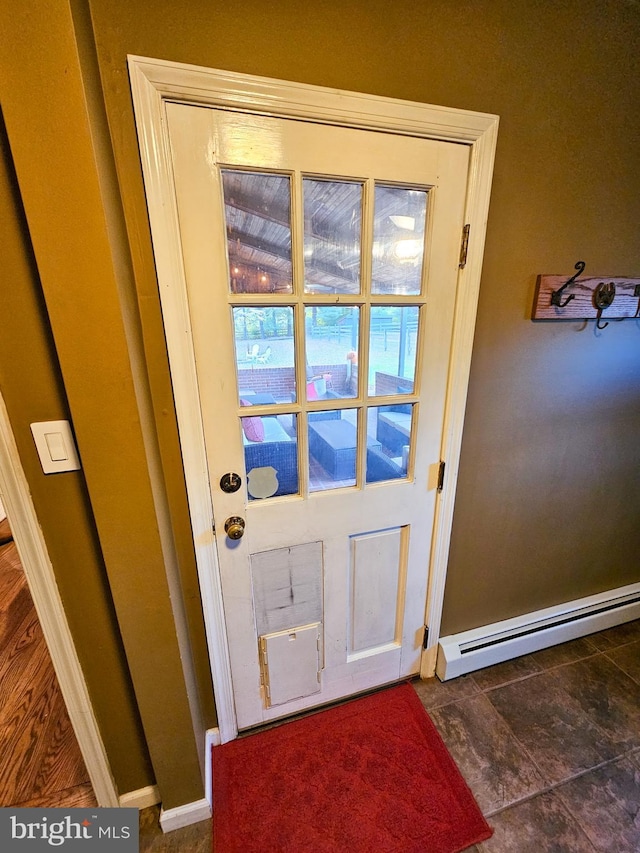 doorway with a baseboard heating unit and baseboards