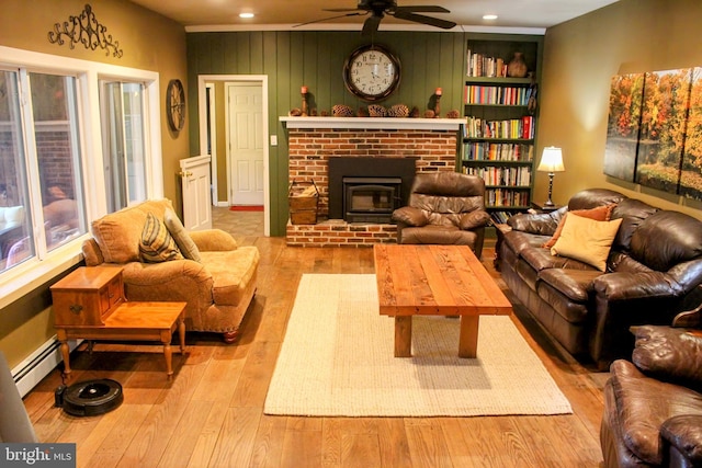 living area featuring baseboard heating, a ceiling fan, wood-type flooring, recessed lighting, and a fireplace