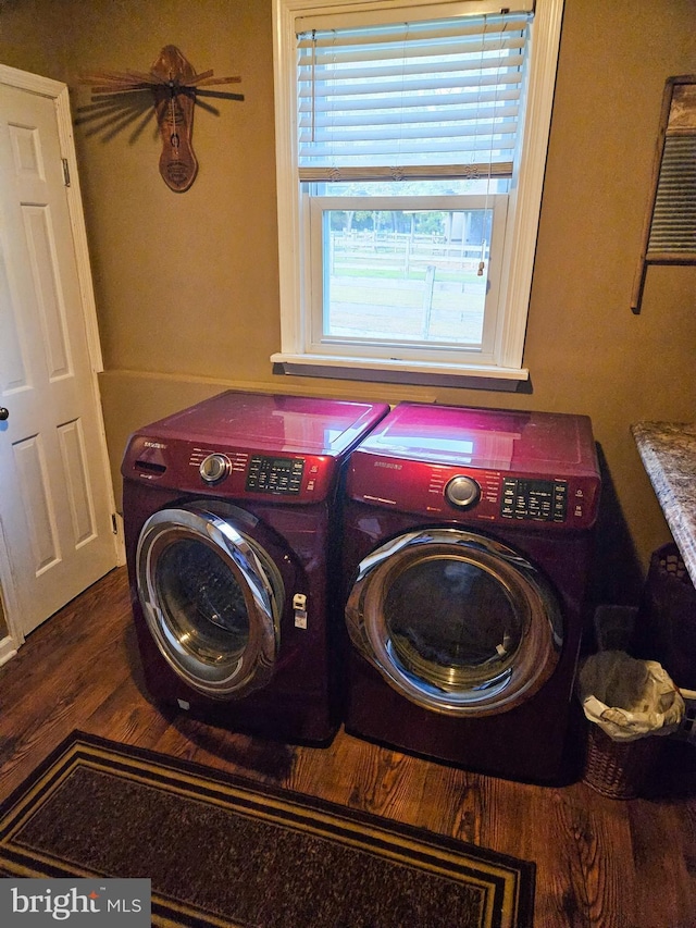 clothes washing area featuring washing machine and dryer and wood finished floors