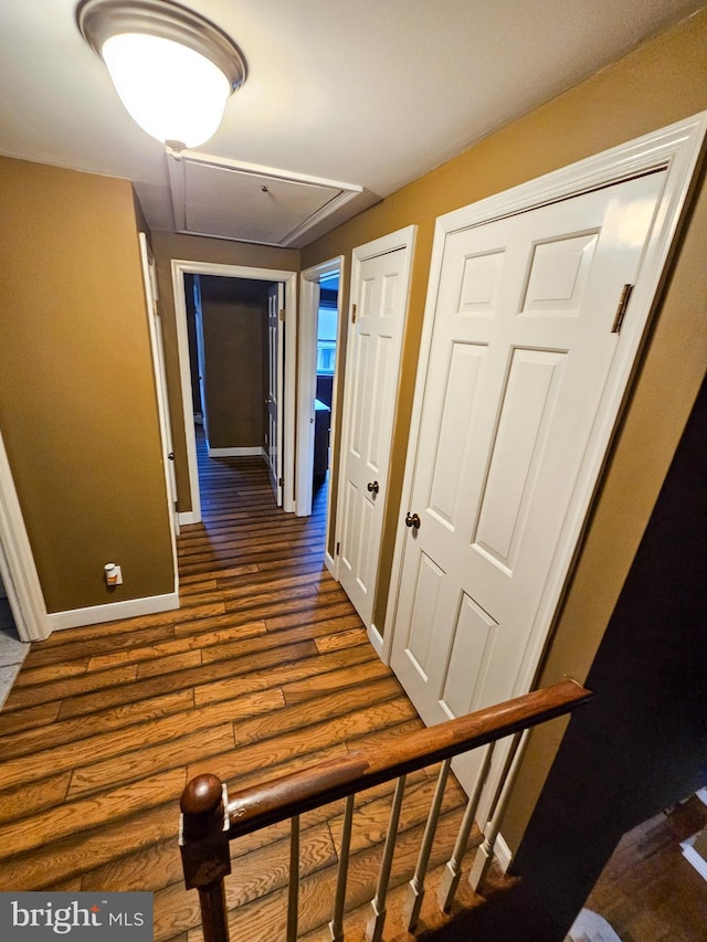 corridor with attic access, dark wood-style flooring, and baseboards