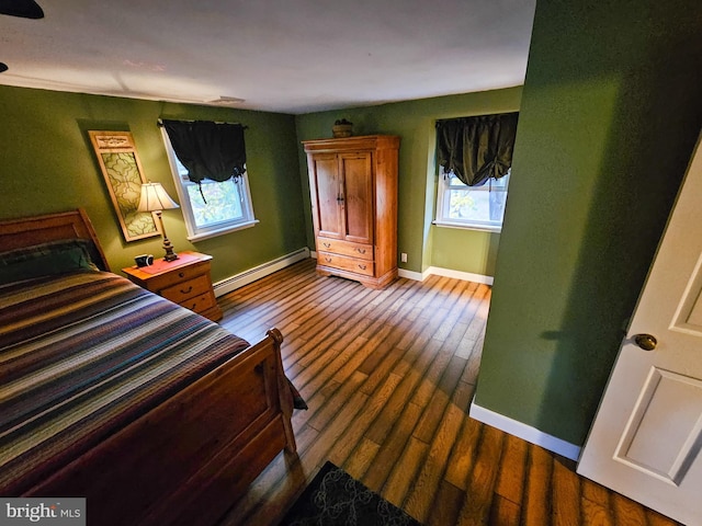 bedroom with a baseboard radiator, multiple windows, and dark wood-style flooring